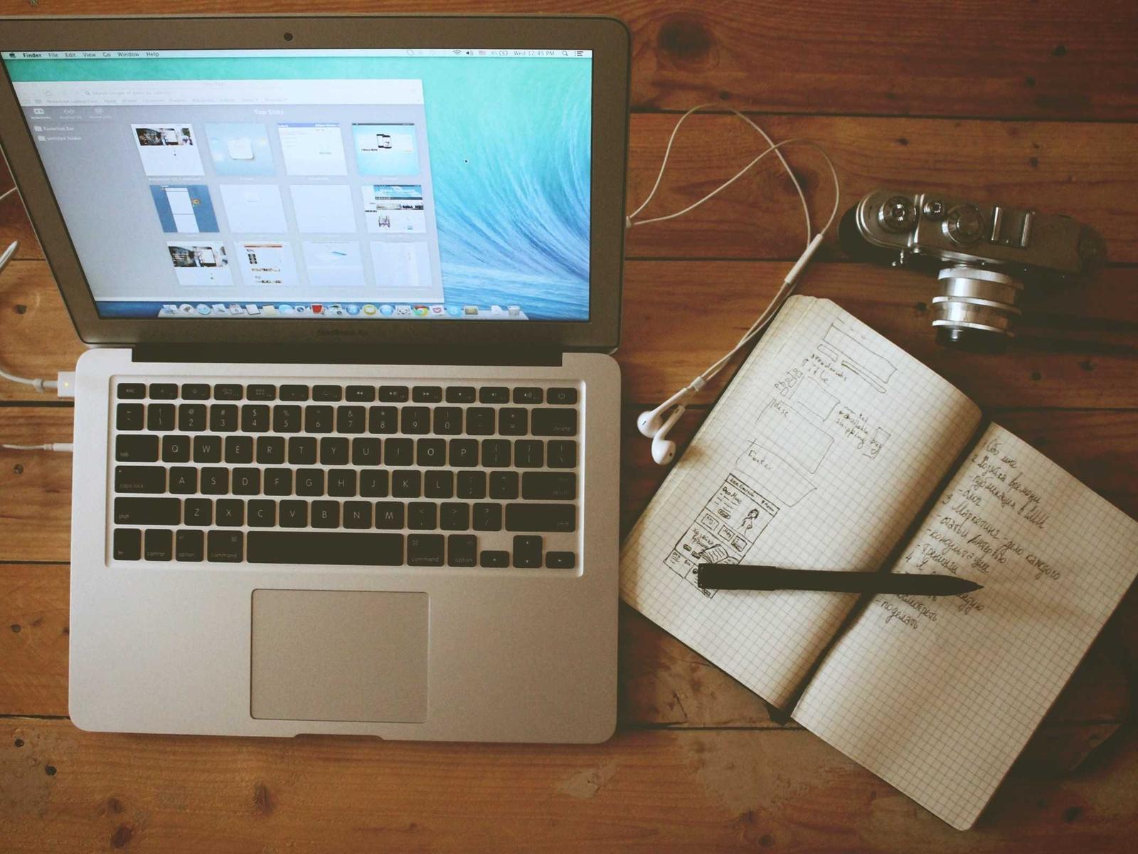 Planejamento de um sistema de design: laptop, wireframes desenhados à mão e câmera sobre a mesa